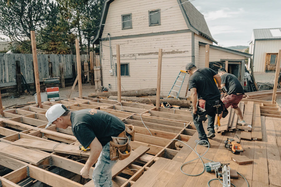 Workers fastening joists across a new deck frame