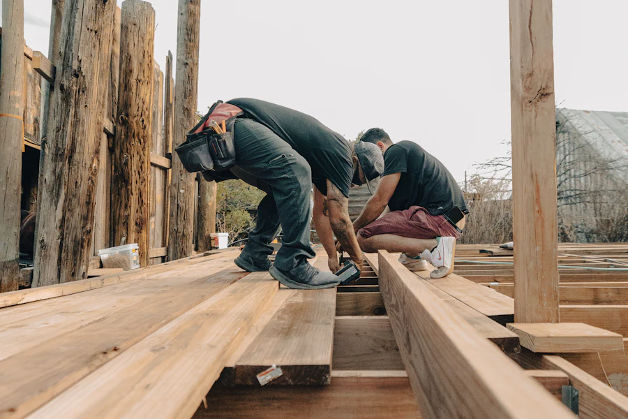 Two workers repairing boards on a wooden deck