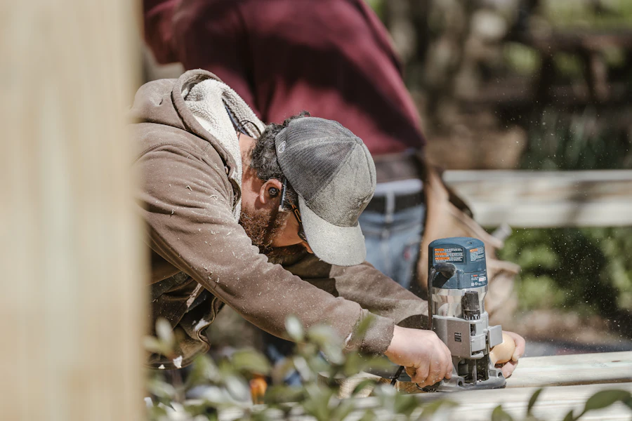 Carpenter guiding a trim router along a deck board